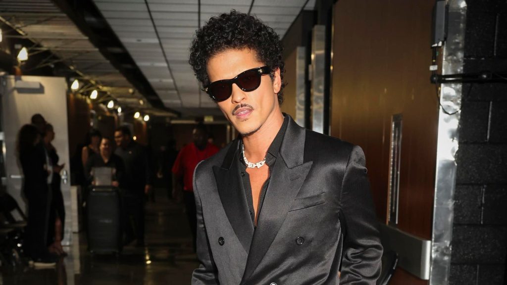 Bruno Mars actuando en vivo con un traje brillante