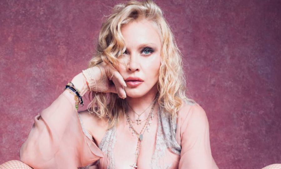 Portada del álbum 'Confessions II' de Madonna, con la artista vestida de morado sobre altavoces y un velo rosa.