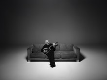Paul Kelly, el cantautor australiano, con una guitarra acústica en un escenario.