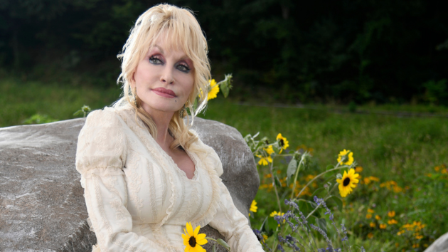 Retrato de Dolly Parton sonriendo, con su característico peinado rubio y vestuario brillante.