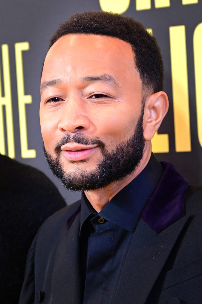 John Legend sonriendo y mirando a la audiencia en una presentación en vivo.